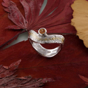 Geschwungener Eisschlagring mit Mandaringranat seitlich Gold und Silber